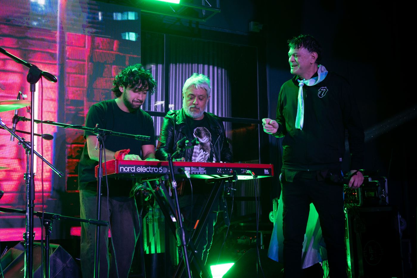 La banda completa sobre el escenario, con teclados y luces verdes