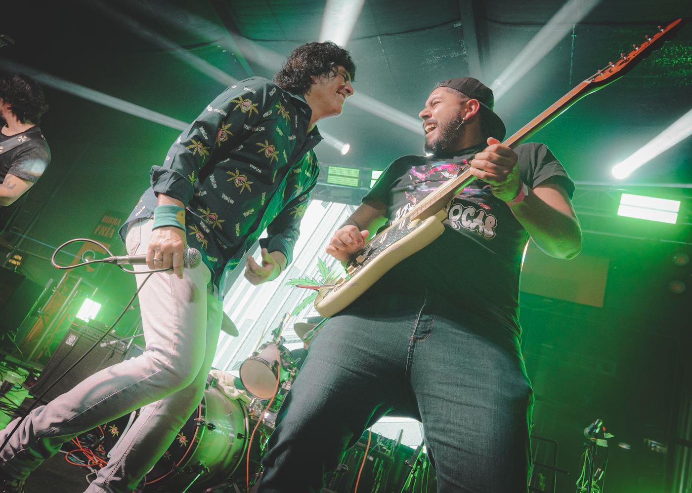Dos músicos tocando bajo luces verdes